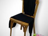 a wooden chair with a black seat and a vase of flowers