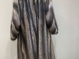 a fur coat on a mannequin stand in front of a wall