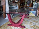 a glass table with a red base in a room