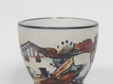 une petite tasse décorée d'une peinture, posée sur une table