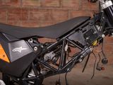 a black and orange motorcycle parked in front of a brick wall