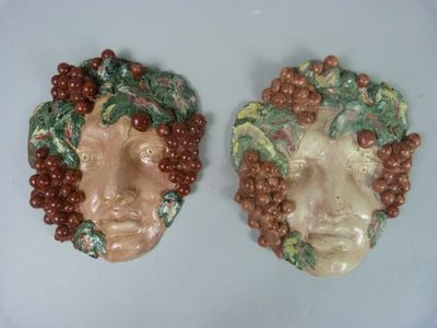 deux figurines en céramique représentant un homme et une femme avec des grappes de raisin sur la tête