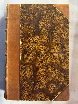 un vieux livre à la couverture brune posé sur une table