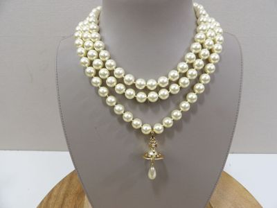 a close up of a necklace with pearls on a mannequin