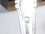 une cuillère en argent posée sur une table, avec une autre cuillère en argent en arrière-plan
