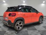 the rear end of an orange citrole parked on a checkered floor