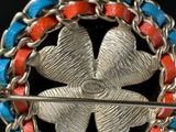 an image of a silver broochle with red and blue beads