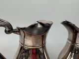 a silver tea pot and a silver tea pot on a table