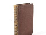 an old book sitting on top of a white table next to a white wall