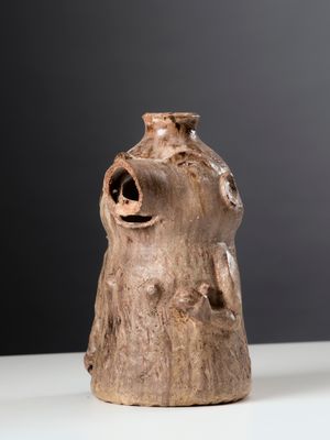 un vase marron posé sur une table sur fond noir