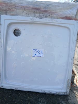 un réfrigérateur blanc posé à même le sol, à côté d'un tas de bois