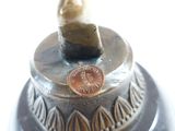 a close up of a metal object with a coin on it