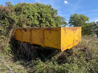a yellow dumpster sitting in the middle of a field