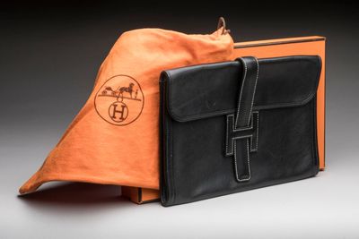 an orange and black bag sitting on top of a table next to a brown bag