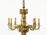 un lustre ancien en laiton à cinq bougies, surmonté d'un oiseau