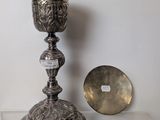 a silver cup sitting on a table next to a silver plate