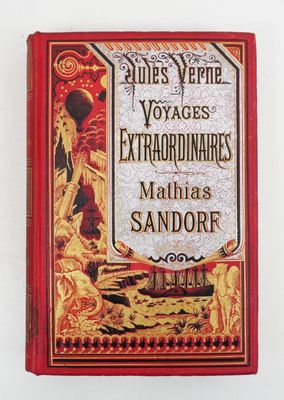 un vieux livre à la couverture rouge posé sur une surface blanche
