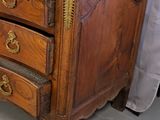 a wooden chest of drawers in a room with a curtain behind it