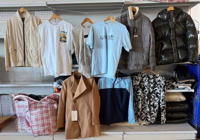 many shirts and pants hanging on a rack in a store
