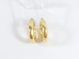 a pair of gold hoop earrings on a clear display stand