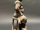 a statue of a man sitting on a chair with a hat on