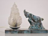 une statue d'éléphant posée sur une table, à côté d'une lampe
