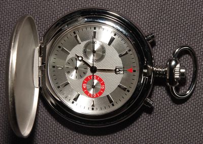 un gros plan d'une montre de poche en argent posée sur une table