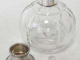 a glass bottle with a silver lid next to a silver cup