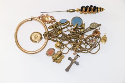 un tas de bijoux en or et en argent posés sur une surface blanche