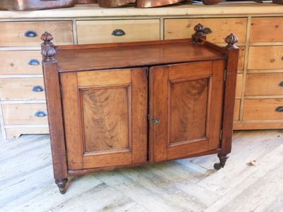 a wooden cabinet in a room with many pots and pans on top of it