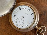 a pocket watch sitting on a wooden table with a magnifying lounder