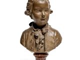 bronze bust of a young boy wearing a bow tie on a pedestal