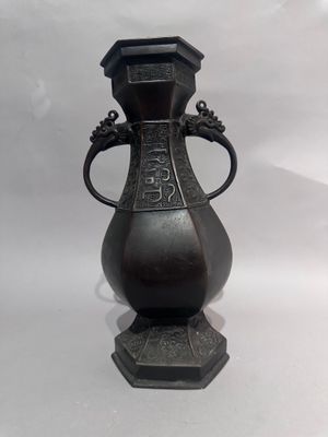 un vase en bronze muni d'une anse et posé sur un socle