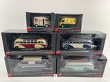 six petits bus jouets emballés dans leurs boîtes, posés sur une surface blanche