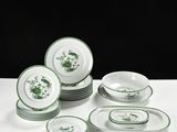 des assiettes et des bols verts et blancs posés sur une table blanche, sur fond noir