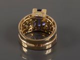 a close up of a gold ring with a blue sapphire and diamonds