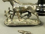 a statue of a horse and a dog on a table next to a vase