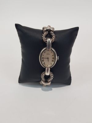 a close up of a wrist watch on a pillow on a white surface