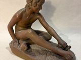 statue of a boy sitting on a rock with a fish in his hand