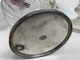 a glass jar with a silver lid sitting on a table next to a candle
