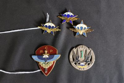 trois épingles et un badge d'épingle sont posés sur une surface noire