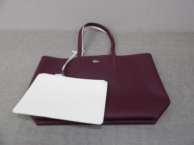 purple and white handbag with a tag attached to it on a gray surface