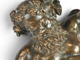 a bronze statue of a man laying down on the ground