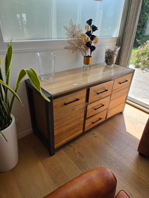 un fauteuil en cuir marron dans un salon, à côté d'une commode en bois