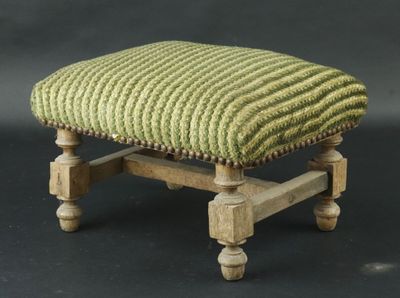 un petit repose-pieds surmonté d'un coussin vert