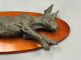 a sculpture of a deer laying on a wooden plate