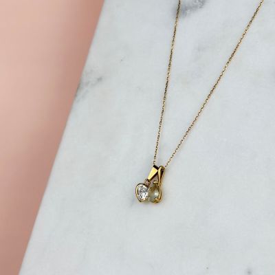 un collier en or avec un pendentif en diamant posé sur une surface en marbre