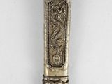 an old silver spoon with a dragon on it sitting on top of a table
