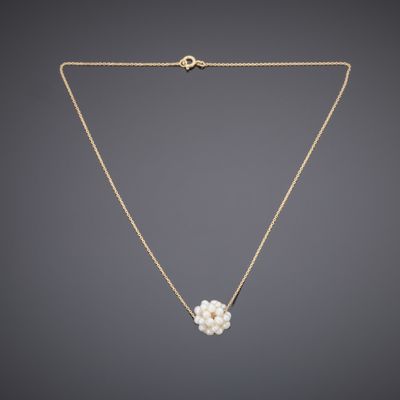 a gold necklace with a pearl flower on a chain
