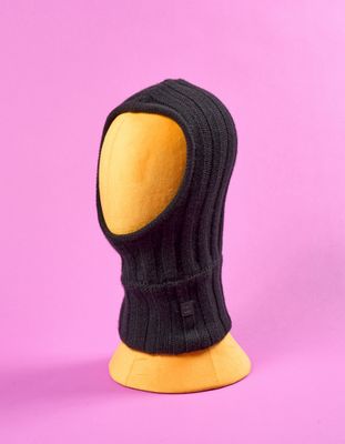 un mannequin en bois coiffé d'un chapeau noir sur fond rose